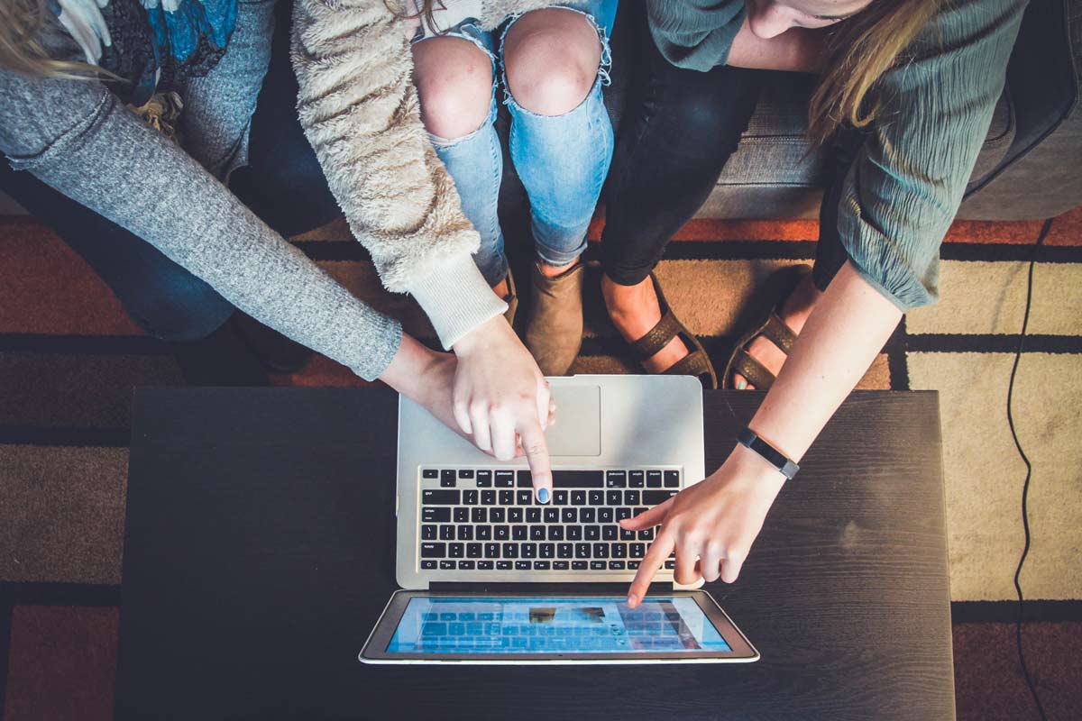 three people pointing at laptop