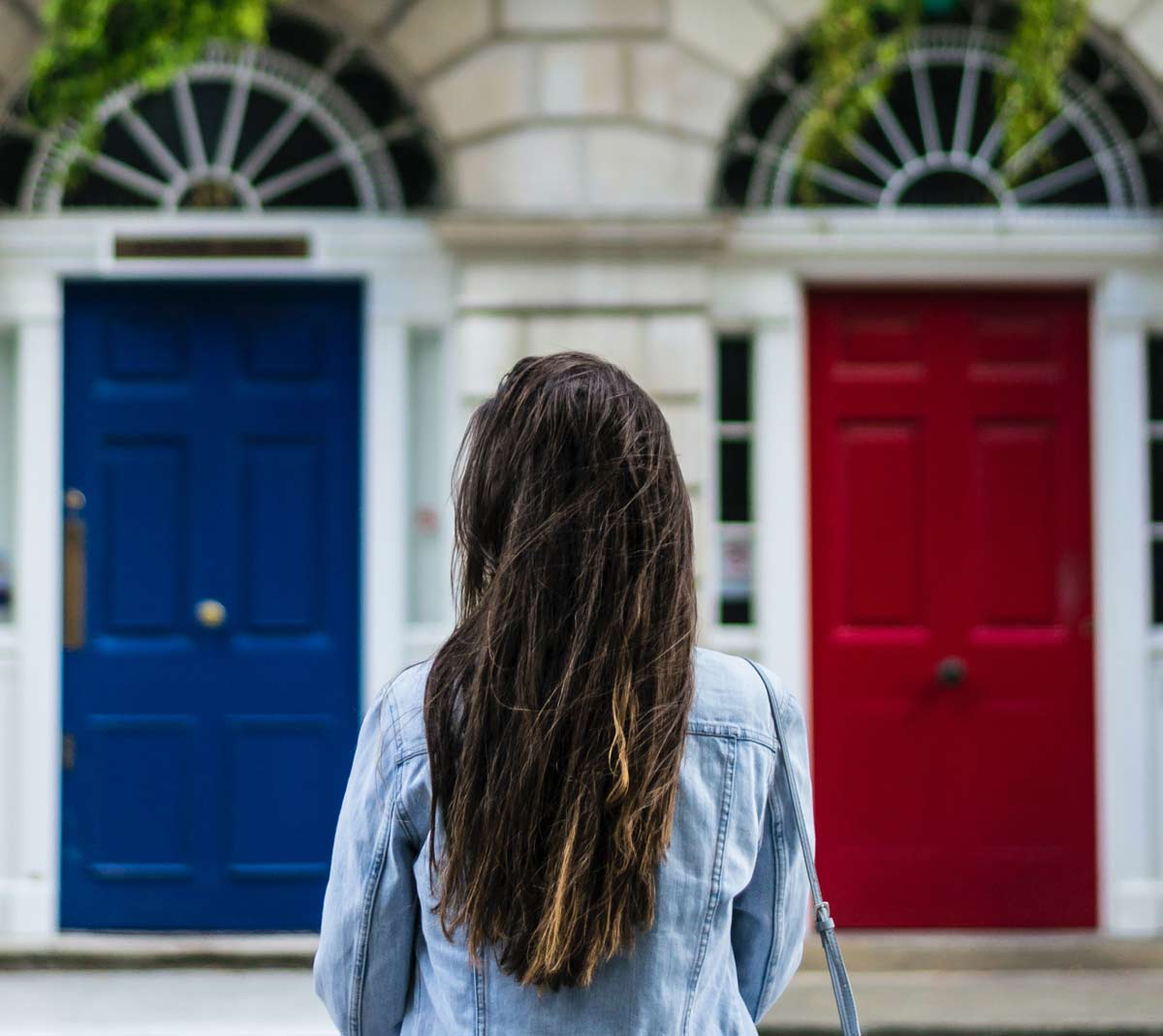 Photograph of a woman stood in front of two different coloured doors.