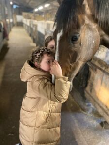 A little girl, Betsy, strokes a racehorse