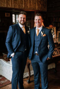 Iain stood next to his brother, Ross dress in three-piece suits.