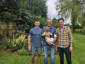 Mark outside with his sons either side and holding his dog
