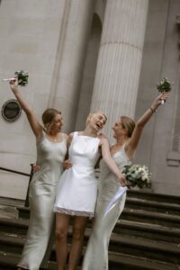Alice Bolton on her wedding day on the steps of the registry office with her sisters all holding flowers