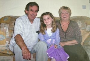 Doug, a young Frankie and Joyce sat on a sofa.
