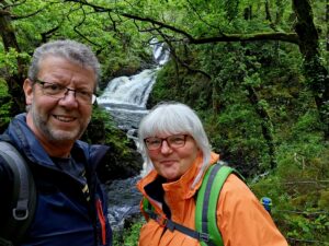 Andi and his wife, Juliette outside in the forest next to a waterfall and stream