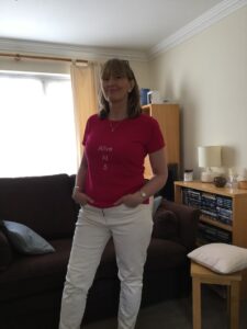 Jude in a living room wearing a pink top that says 'alive at 5'