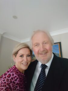 Clare McMillan with her husband both dressed smartly smiling at the camera